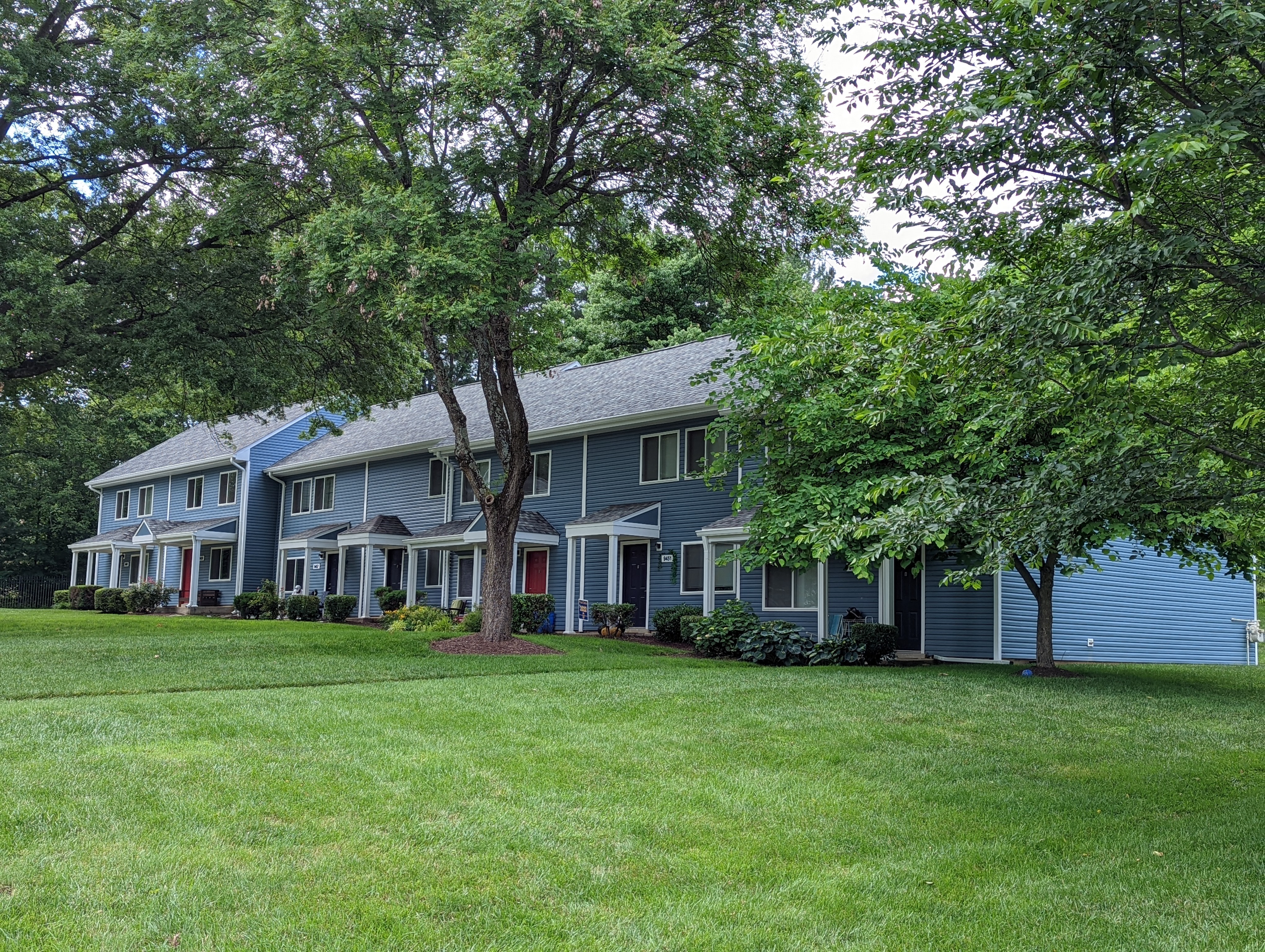 A large house with a red door and a tree in front.